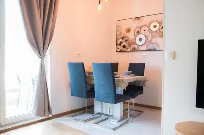 a dining room with a table and blue chairs at Apartman Palma, Budva in Budva