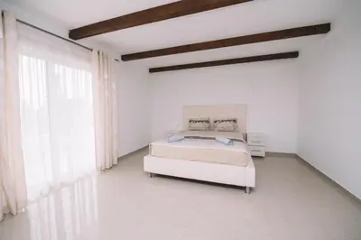 a white bedroom with a bed and a large window at CORONA Apartments in Ulcinj