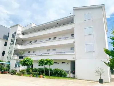 a white building with trees in front of it at CORONA Apartments in Ulcinj