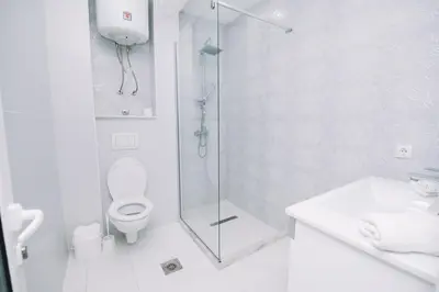 a white bathroom with a shower and a toilet at CORONA Apartments in Ulcinj