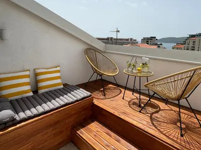 a balcony with a bench and two chairs and a table at SunJourney Apartment SEA view in Becici