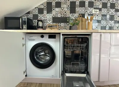 a washing machine in a kitchen under a counter at SunJourney Apartment SEA view in Becici