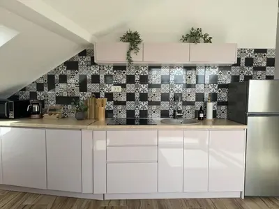 a kitchen with white cabinets and a tile wall at SunJourney Apartment SEA view in Becici