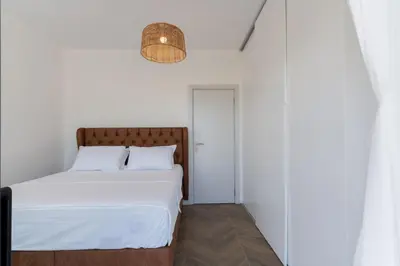 a white bedroom with a bed and a lamp at Family House Giardino Verde in Bar