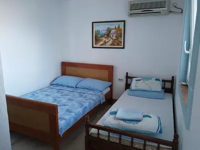 a bedroom with two beds and a tv at Apartmanes Volaric M in Sutomore