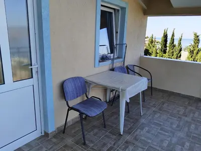 a table and chairs on a balcony with a window at Apartmanes Volaric M in Sutomore