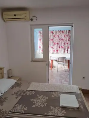 a bedroom with a bed and a table and a window at Apartmanes Volaric M in Sutomore