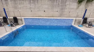 a swimming pool with blue water and chairs in it at Montenegro Apartments Phoenix With Pool in Bar
