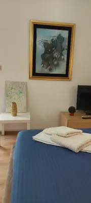 a bedroom with a blue bed with a painting on the wall at Helen's apartments in Budva