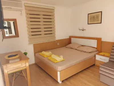 a bedroom with a bed and a table and a window at Helen's apartments in Budva