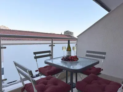 a table with a bottle of wine and fruit on a balcony at Status-M Apartments Irysh in Becici