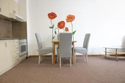 a dining room table with chairs and a vase of flowers on the wall at Status-M Apartments Irysh in Becici