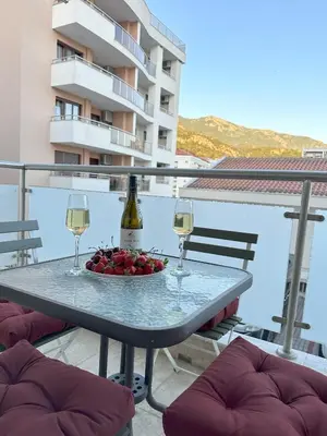 a table with wine glasses and a bowl of fruit on a balcony at Status-M Apartments Irysh in Becici