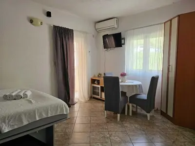 a bedroom with a bed and a table with chairs at Apartments Carpe Diem in Kotor