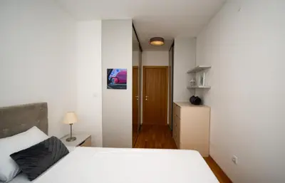 a bedroom with a white bed and a wooden floor at Comfort Residence Art Zone in Podgorica