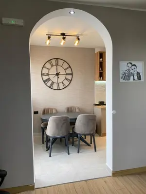 a dining room with a clock and a table and chairs at Original Sunny place in Podgorica