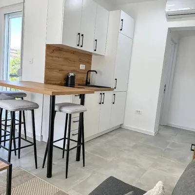 a kitchen with white cabinets and a table and stools at Sea Star in Bar