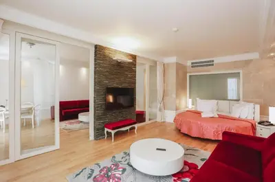 a bedroom with a red bed and a living room at The Unique Splendid Conference Spa Resort Family apt suite sleeps 6 in Becici