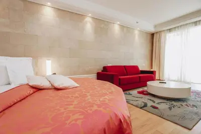 a bedroom with a large bed and a red chair at The Unique Splendid Conference Spa Resort Family apt suite sleeps 6 in Becici