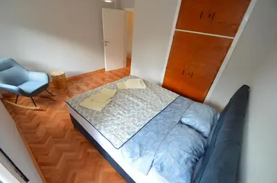 a small bedroom with a bed and a blue chair at MD Residence in Kotor