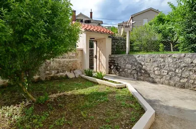 a house with a stone wall and a yard at MD Residence in Kotor