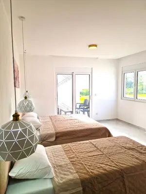 two beds in a room with two windows at IVANA Apartments in Ulcinj