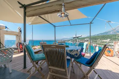 a table and chairs under an umbrella on a deck at Apartment Carpe Diem with the best sea view, Utjeha Montenegro Mediterranean Eu in Masline