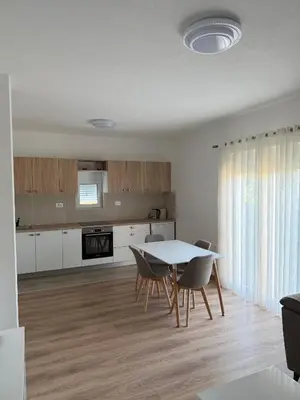 a kitchen and dining room with a table and chairs at Dane Apartment Airport Podgorica in Mitrovići