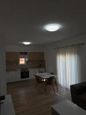 a kitchen with a table and chairs in a living room at Dane Apartment Airport Podgorica in Mitrovići