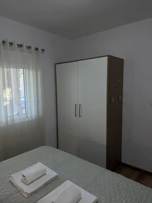 a bedroom with a bed with two towels and a mirror at Dane Apartment Airport Podgorica in Mitrovići