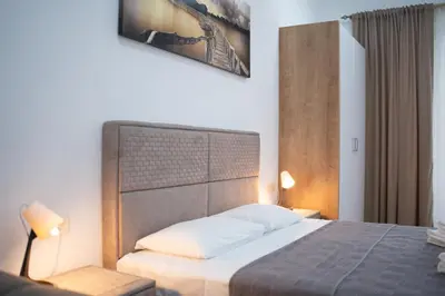 a bedroom with a large bed with a wooden headboard at Dane Apartment Airport Podgorica in Mitrovići