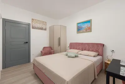 a bedroom with a bed and a chair and a door at Apartments TIME in Kotor