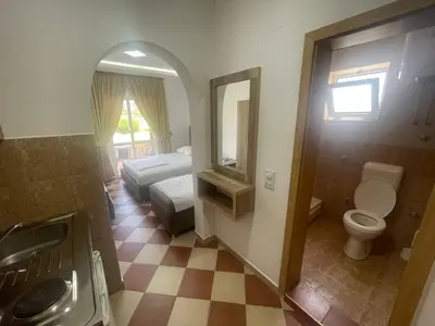 a bathroom with a toilet and a bed and a mirror at Kodra Apartments in Ulcinj