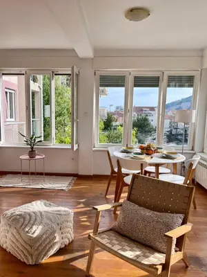 a living room with a table and chairs and windows at Sunny apartments in Budva
