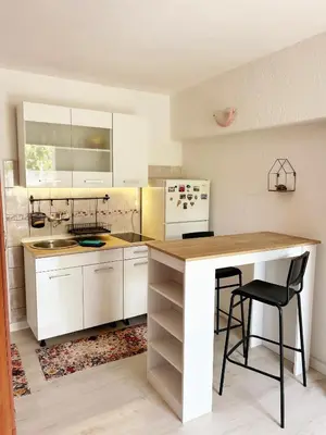 a kitchen with white cabinets and a table and a counter at Zinzula apartments in Bar