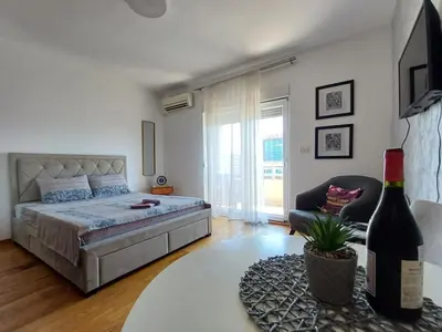 a bedroom with a bed and a chair and a table at Apartman City kvart pg in Podgorica