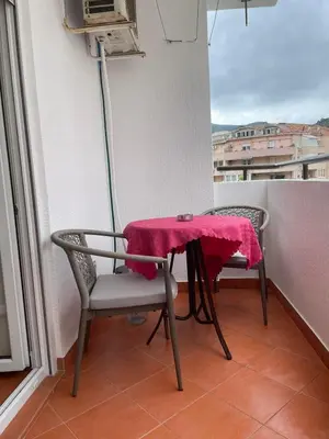 a table and chairs on a balcony with a red cloth at Dado Budva Apartment in Budva