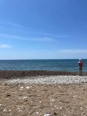 a person standing on a rocky beach near the ocean at Dado Budva Apartment in Budva