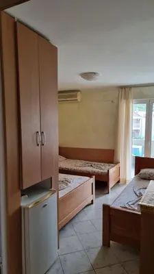 a bedroom with two beds and a cabinet and a window at Apartmani Boskovic in Sutomore