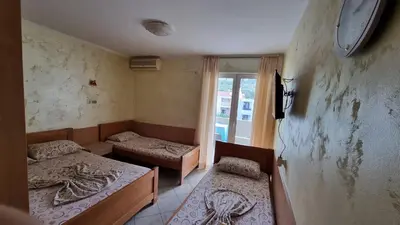 a room with two beds and a clock on the wall at Apartmani Boskovic in Sutomore