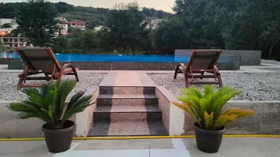 two chairs and plants sitting next to a pool at Lula Apartments in Ulcinj