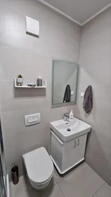 a white bathroom with a toilet and a sink at Studio-apartman Aroma in Bar