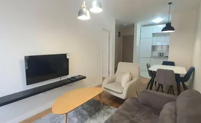 a living room with a couch and a tv on a wall at Sabina apartment City kvart in Podgorica
