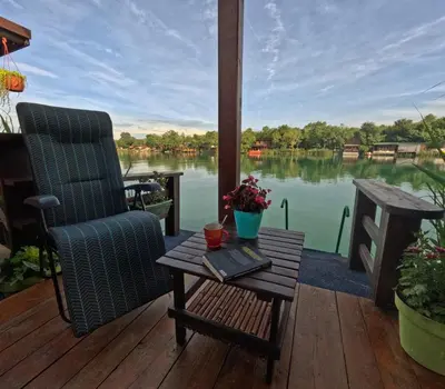 a patio with a table and a chair and a view of a lake at Bamboo River House in Ulcinj
