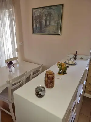 a kitchen with white counters and a table and chairs at Ana apartment City kvart in Podgorica