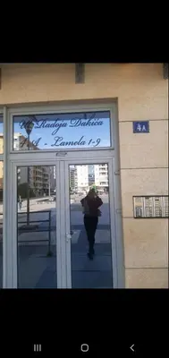 a person walking into a building with an umbrella at Ana apartment City kvart in Podgorica