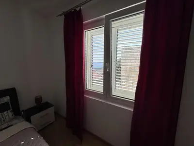 a bedroom with a bed and two windows with red curtains at Villa Happy Family in Seoca