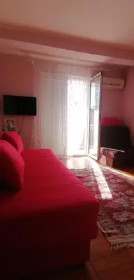 a bedroom with a red bed and a window at Marko Apartmani in Budva