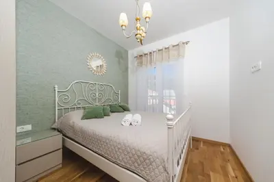 a bedroom with a white bed and a chandelier at Nest 1 in Becici
