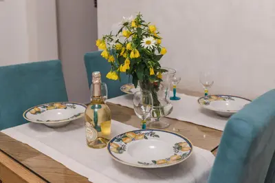 a table with plates and a bottle of wine and flowers at Nest 1 in Becici